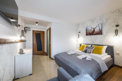 a bedroom with a king sized bed with yellow pillows at Biały Jeleń z basenem i jacuzzi in Białka Tatrzanska