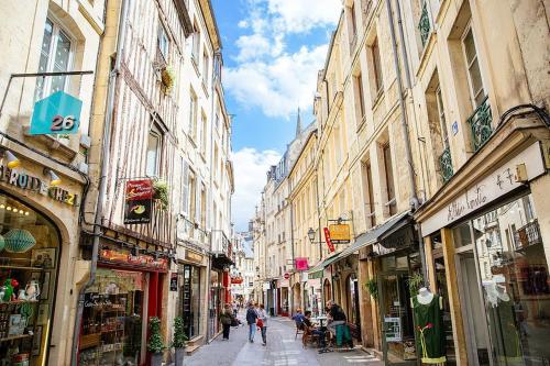 a city street with buildings and people walking down it at L'expérience d'Elie by Icone Collection in Caen