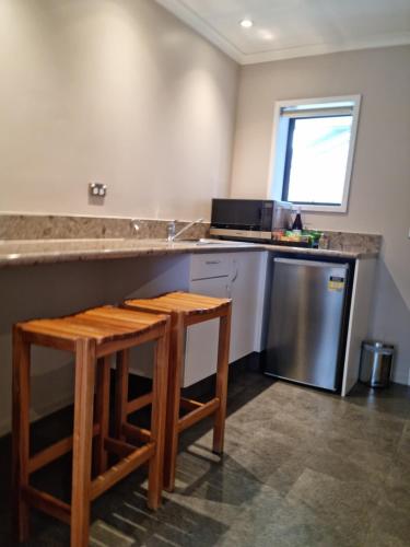 a kitchen with a counter and two stools at Paroa Hotel in Greymouth