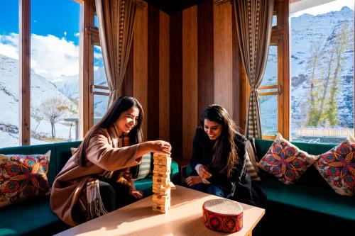 two women sitting on a couch playing a game on a table at Zostel Sissu in Sissu