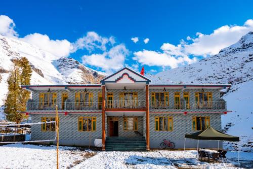 a house in the snow with mountains in the background at Zostel Sissu in Sissu