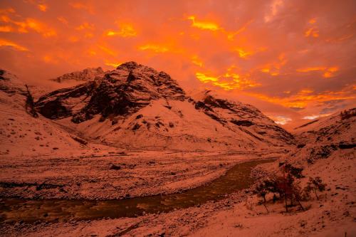 a mountain covered in snow with a sunset in the background at Zostel Sissu in Sissu