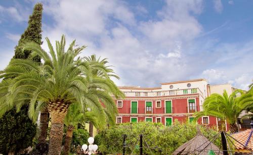 a large building with palm trees in front of it at Hotel Antiga in Calafell