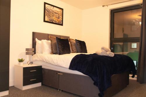 a bedroom with a bed with a black blanket on it at LiveStay-Modern Apartment Minutes Away From Heathrow in Slough