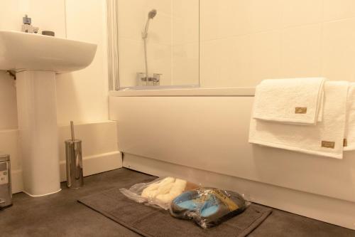 a bathroom with a sink and a shower and a rug at LiveStay-Modern Apartment Minutes Away From Heathrow in Slough