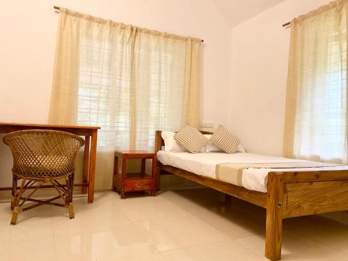 a bedroom with a bed and a chair and a window at Tattwamasi Ayuryoga with Breakfast and Yoga in Varkala