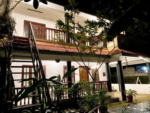 a house with a balcony and plants in front of it at Tattwamasi Ayuryoga with Breakfast and Yoga in Varkala