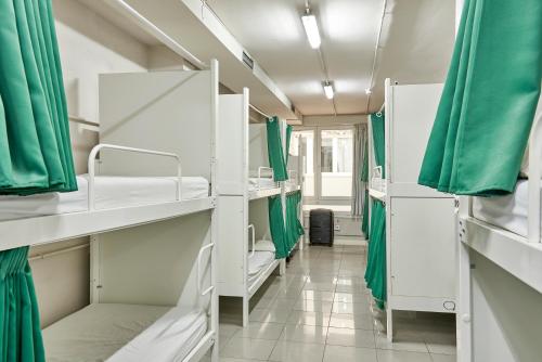 Pokój z białymi łóżkami piętrowymi i zielonymi zasłonami w obiekcie Hola Hostal Eixample w Barcelonie
