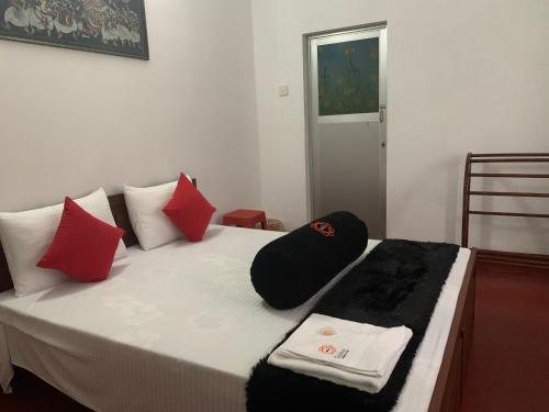 a bedroom with a bed with red and black pillows at Sobha Holiday Home in Anuradhapura