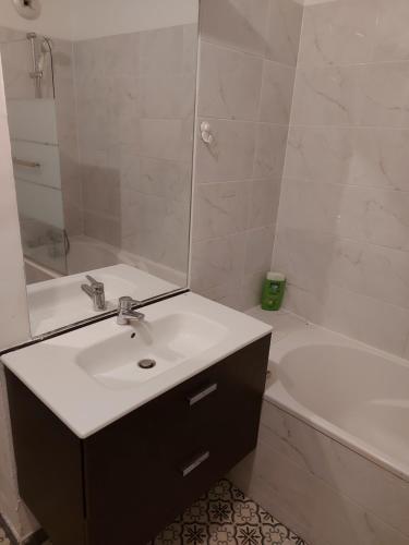 uma casa de banho com um lavatório, um espelho e uma banheira em Bienvenue dans beau T2 de 48m2 à Gennevilliers em Gennevilliers