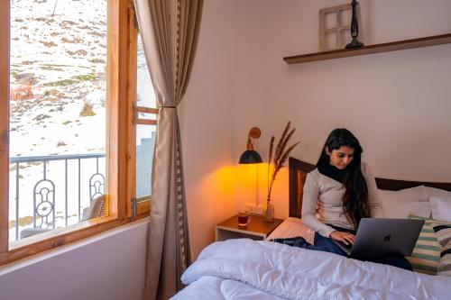 a woman sitting on a bed using a laptop at Zostel Sissu in Sissu