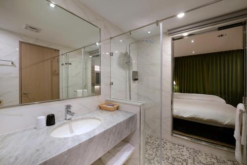 a bathroom with a sink and a mirror and a bed at Aeris International Hotel in Taichung