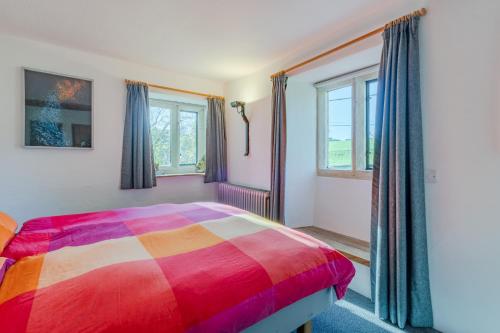 a colorful bed in a room with windows at The Barracks in Northleach