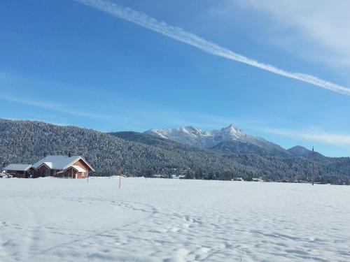 pokryte śniegiem pole z domem i górami w obiekcie Chalet Josi w mieście Leutasch