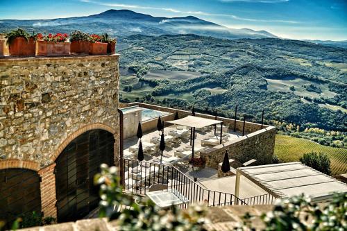 a patio with a table and a view of the mountains at Castello di Velona Resort, Thermal SPA & Winery in Montalcino