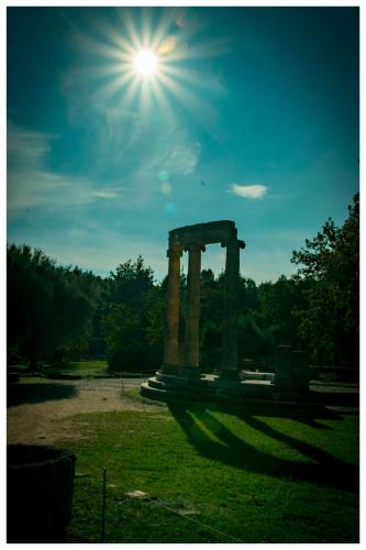 a sun shines over a stone monument in a field at Arcadianis lakeview villa at Psari Arkadias in Psárion