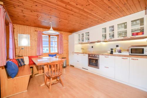a kitchen with white cabinets and a wooden ceiling at Chalet Castellani Apartment in Fiesch