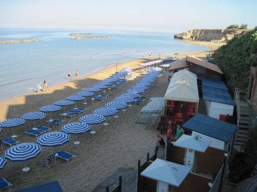 a beach with blue and white umbrellas and people on it at Bed and Breakfast Villa Viviana in Anzio