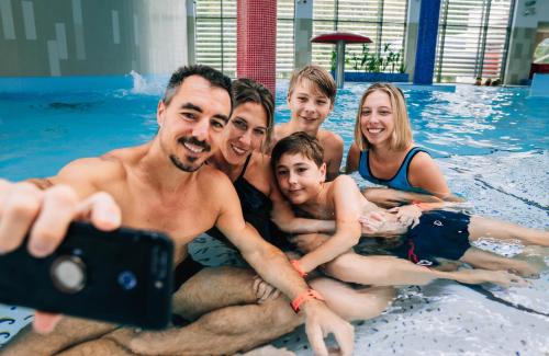 a man taking a picture of a family in a swimming pool at Thermal Hotel Balance Lenti in Lenti