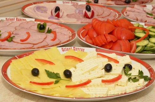 a table topped with plates of food with cheese and vegetables at Hotel Orient Galati in Galaţi