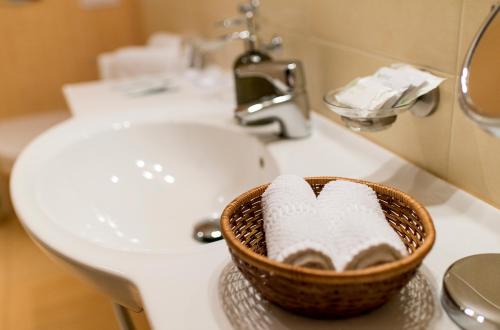 a basket of towels sitting on a bathroom sink at Hotel Pušyno Namai in Tirkšliai