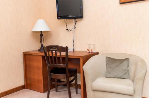 a room with a desk with a chair and a television at Hotel Pušyno Namai in Tirkšliai