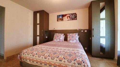 ein Schlafzimmer mit einem großen Bett mit einer farbenfrohen Tagesdecke in der Unterkunft Maison charmeur avec jardin à Puy-l'Évêque et piscine partagée in Puy-lʼÉvêque