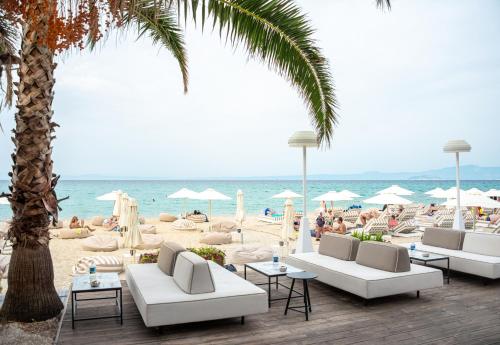 a beach with white couches and people on the beach at Tridente Mare Apart Hotel in Pefkohori