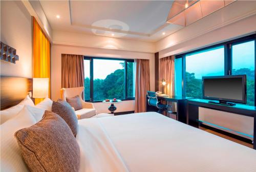 a hotel room with a bed and a television at The Raintree, St. Mary’s Road in Chennai