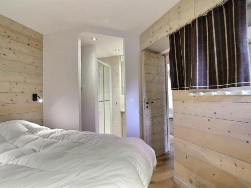 メリベルにあるAppartement Méribel, 3 pièces, 7 personnes - FR-1-182-184の白いベッドと木製の壁が備わるベッドルーム1室が備わります。