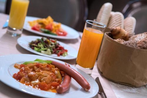 a table with plates of food and two glasses of orange juice at Residence Hotel Balaton in Siófok