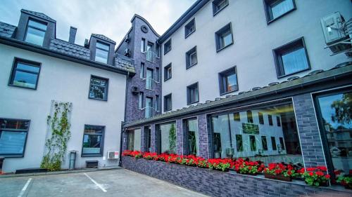 a white building with red flowers in front of it at Hotel Senator Konferencje & SPA in Starachowice