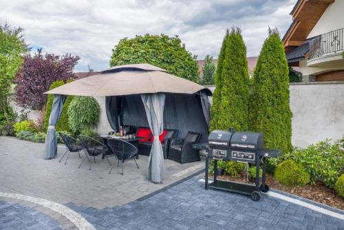 a backyard with a grill and an umbrella at Biały Jeleń z basenem i jacuzzi in Białka Tatrzanska