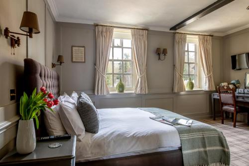 um quarto com uma cama, uma secretária e janelas em The Running Horses em Mickleham