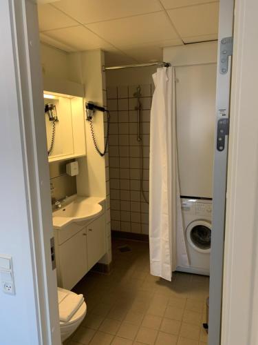 a bathroom with a toilet and a sink and a washing machine at Nuuk Hotel Apartments by HHE in Nuuk