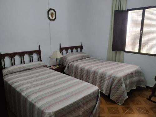 two beds in a hotel room with a window at Casa Rural San Antonio in La Puebla de los Infantes