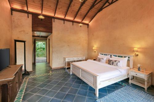 a bedroom with a large white bed and a flat screen tv at Amritara Aura Resort & Spa in Mandrem