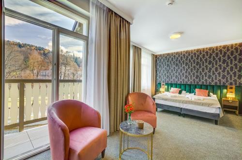 a hotel room with a bed and a large window at Hotel Willa Tatrzańska in Krynica Zdrój