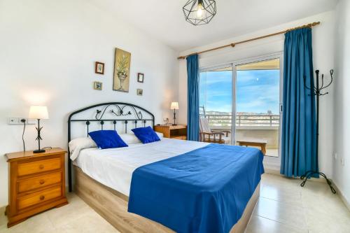 Un dormitorio con una cama con sábanas azules y una ventana. en Homeincalpe Apolo XVII 1-14-41, en Calpe