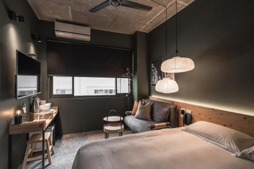 a bedroom with a bed and a desk and a couch at SI Hotel in Taichung