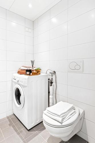 a white bathroom with a washing machine and a toilet at BJØRVIKA APARTMENTS, Teaterplassen, Oslo city center in Oslo
