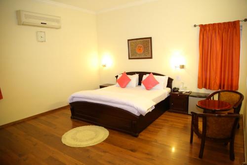 a bedroom with a bed and a table and a chair at Swan Suites Madhapur in Hyderabad