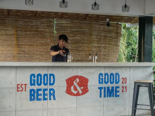 un hombre parado detrás de un mostrador en un bar en Siargao Bed and Brewery, en General Luna