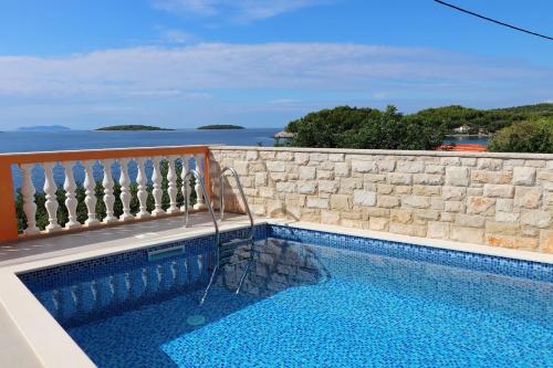 einen Pool neben einer Steinmauer und dem Meer in der Unterkunft Holiday Home Adriatic View in Prizba