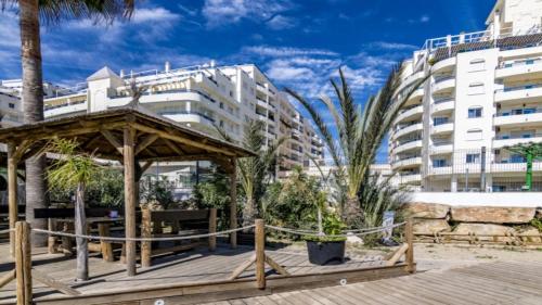 een houten terras met een prieel en gebouwen bij Apartamento 103 in Marbella