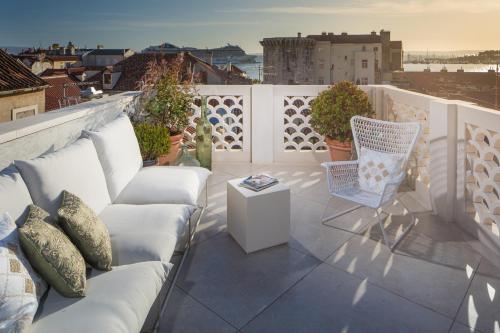 a patio with a couch and a chair on a balcony at Judita Palace Heritage Hotel in Split