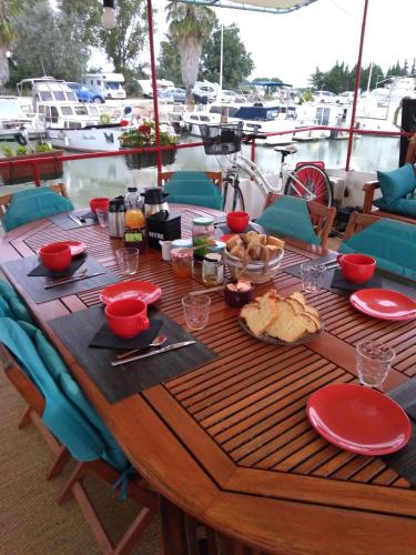 een houten tafel met eten op een boot bij PENICHE FARNIENTE CLIMATISEE - Aux Portes de la Camargue in Bellegarde
