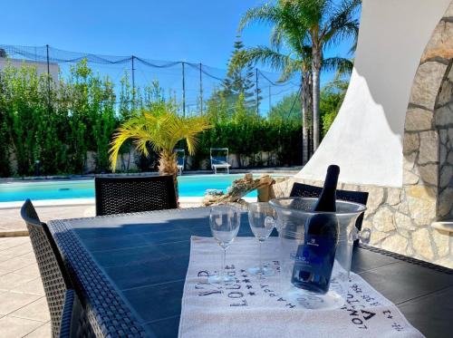 a table with glasses and a bottle of wine at Villa Francesca in Fontane Bianche