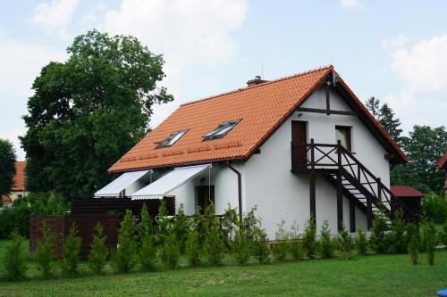 una casa blanca con techo naranja en Mazurska Apartamenty en Rydzewo