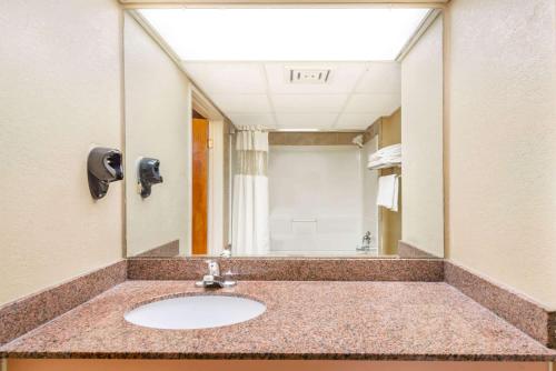 a bathroom with a sink and a large mirror at Ramada by Wyndham West Atlantic City in West Atlantic City